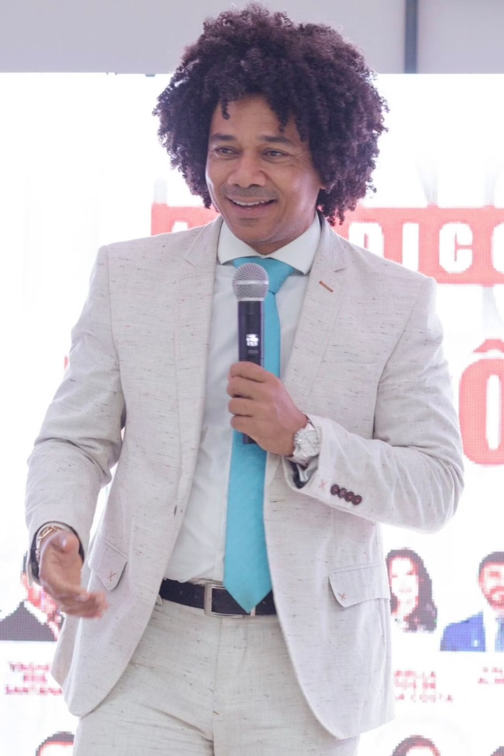 Prof. Marinho Soares discursando em evento, segurando microfone
